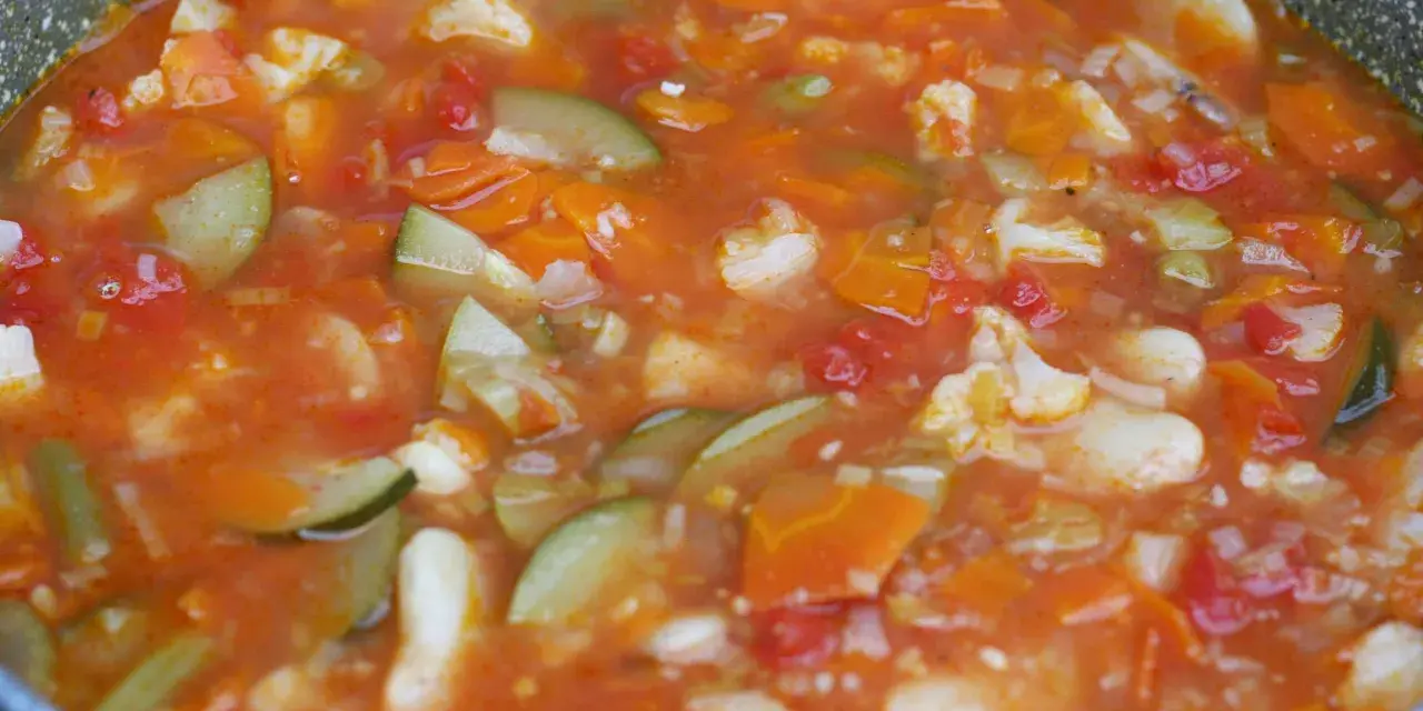 Gęsta, aromatyczna zupa jarzynowa, przypominająca włoskie minestrone, z kawałkami marchewki, cukinii i kalafiora w pomidorowym sosie.