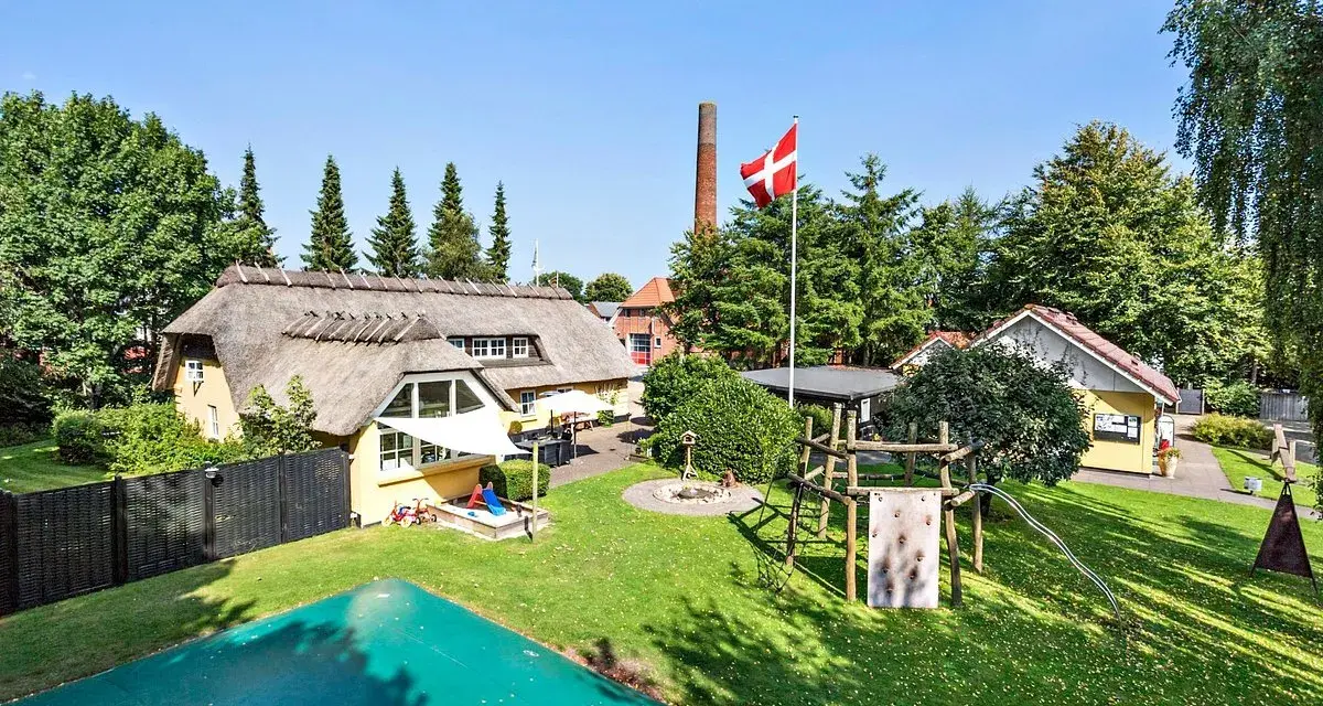 En idyllisk campingplats i Billund med halmtak, lekplats och danska flaggan vajande stolt.