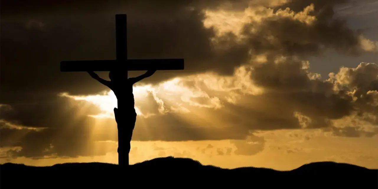 Silhouette of Jesus on the cross against a dramatic sky. His sacrifice shows Jesus died for our sins, offering hope.
