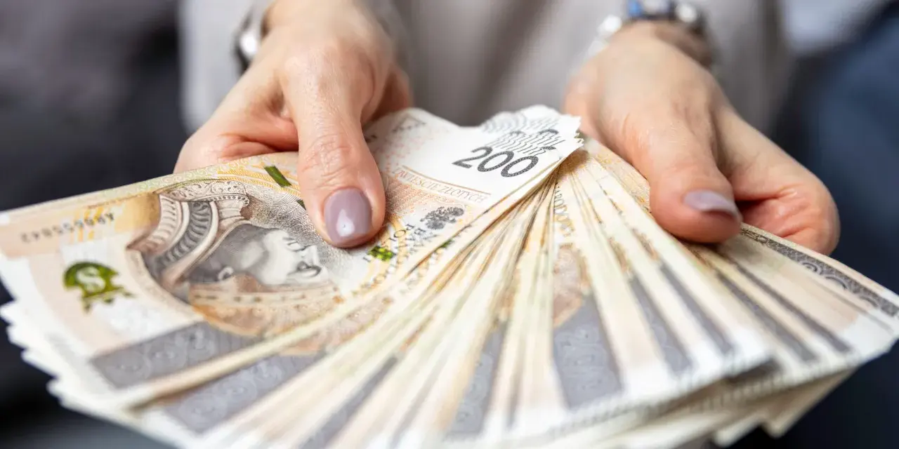 Dłonie trzymające plik banknotów 200 zł. Pytanie o to, ile zarabia hotelarz, często wiąże się z takimi widokami.