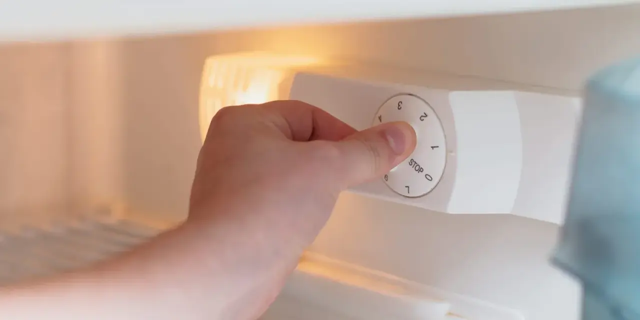 Main tenant ajuste la molette pour régler la quelle temperature congelateur. Le bouton indique "STOP" et des chiffres de 0 à 7.