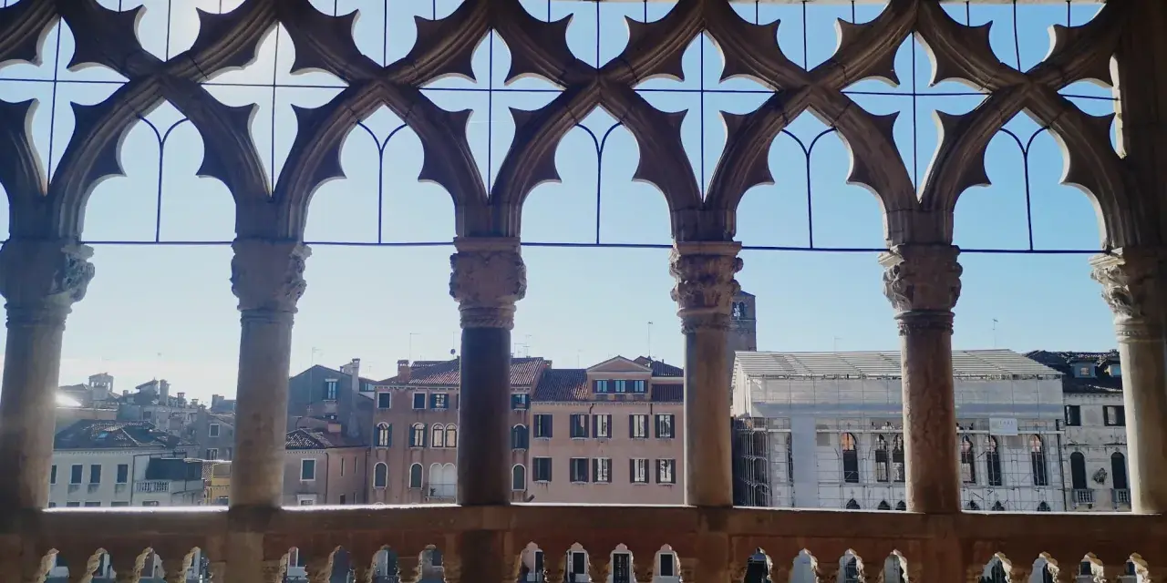 Finestra gotica con vista sul Canal Grande, gondole e palazzi veneziani, tra cui la Ca' d'Oro.