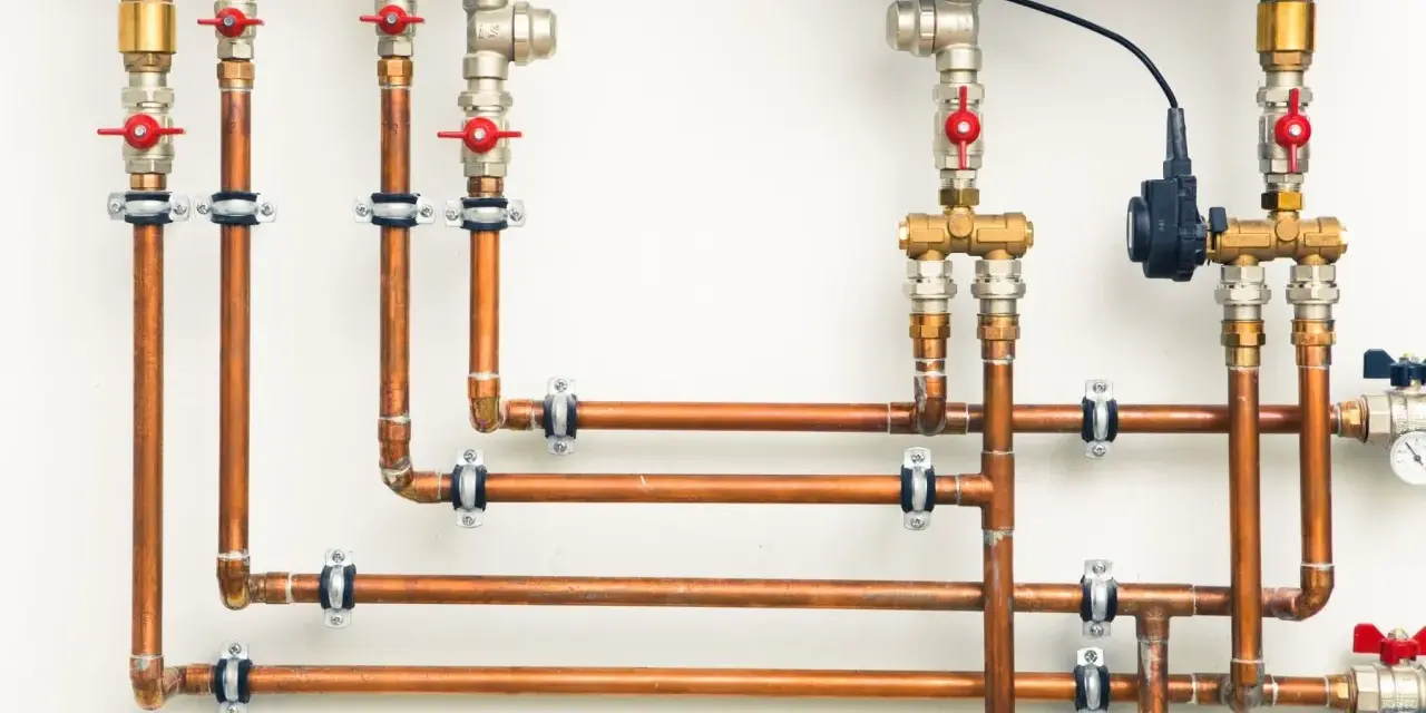 System hydrauliczny z miedzianymi rurami i zaworami. Różnica między złączkami PEX U czy TH jest kluczowa dla szczelności instalacji.