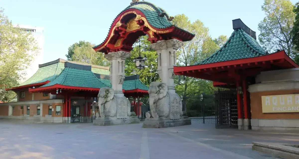 Eingang zum zoologischer garten mit asiatischer Architektur, Elefantenstatuen und grünen Dächern.