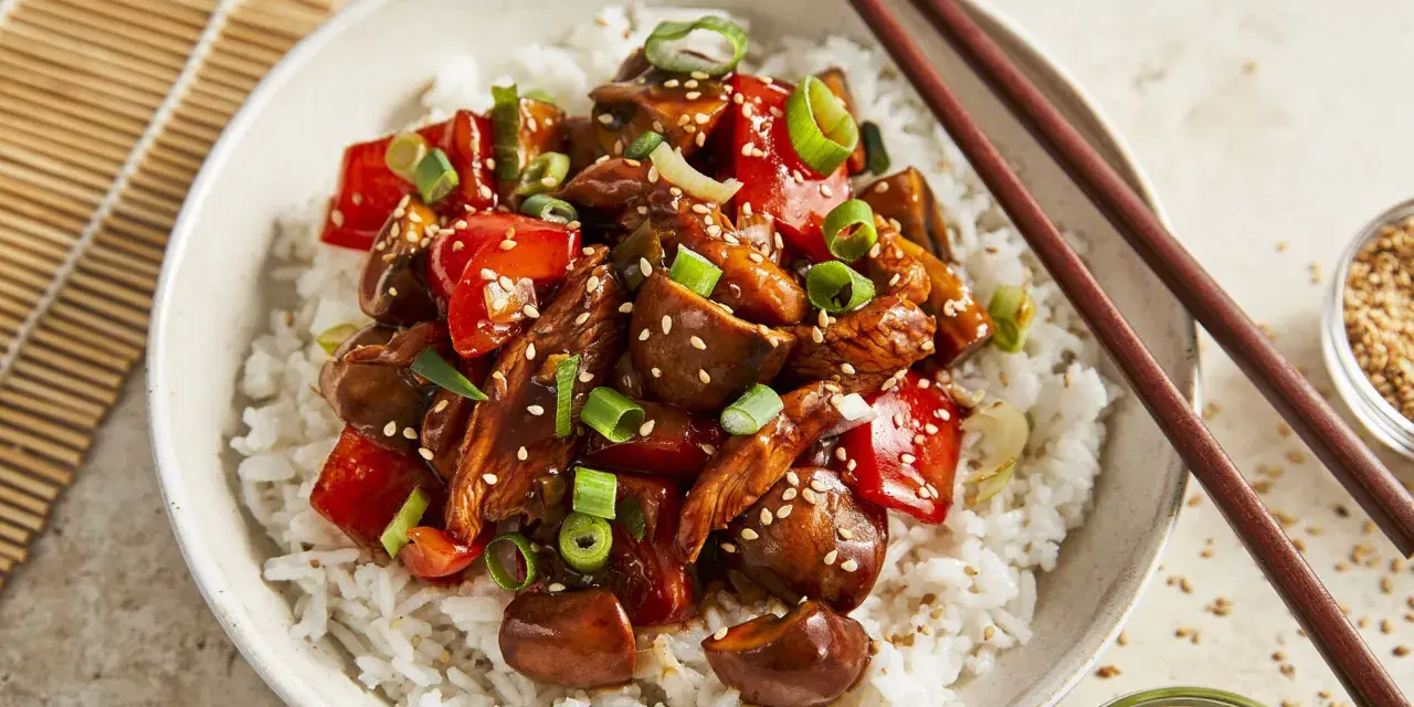 Schüssel mit Reis und einem köstlichen Chicken Teriyaki, garniert mit Frühlingszwiebeln und Sesam.