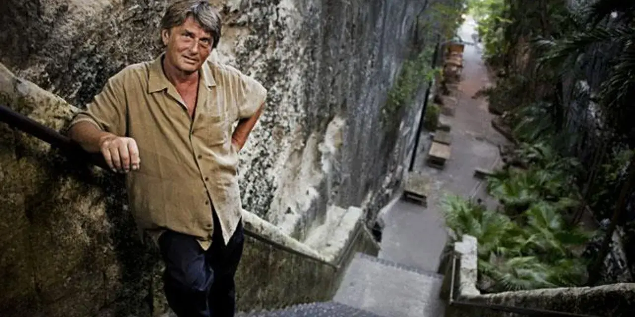 Mike Oldfield, znany muzyk, stoi na kamiennych schodach. Może to miejsce, gdzie mieszkał z żoną.