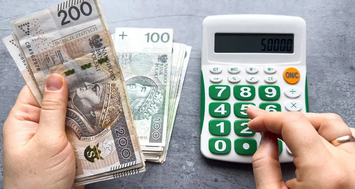 Ręka z polskimi banknotami 200 zł i 100 zł obok kalkulatora z wyświetloną kwotą 50000. Planowanie waloryzacji emerytury 2026.