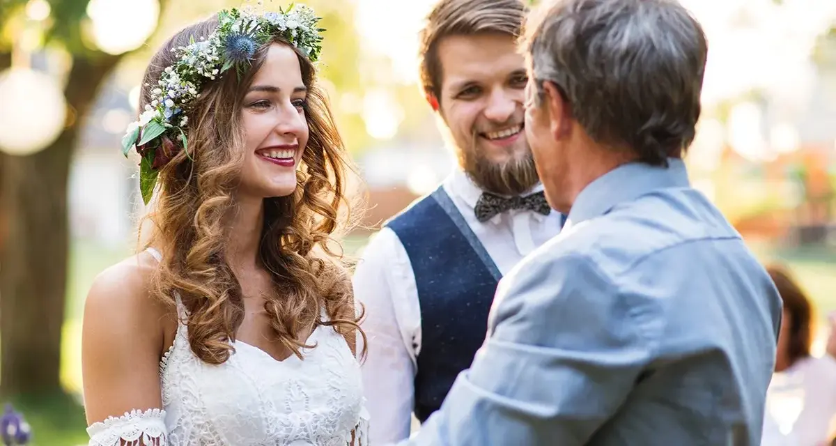 Panna młoda w wianku i pan młody słuchają ojca udzielającego im tradycyjne błogosławieństwo.