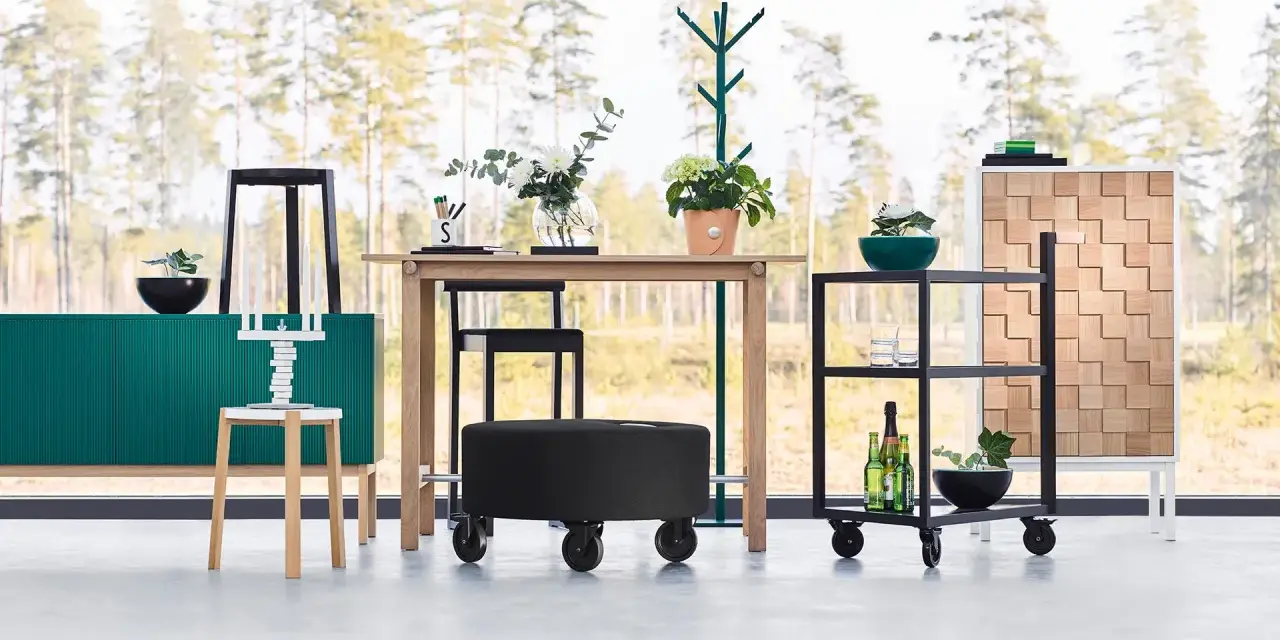 Inredning med en grön skänk, träbord, svarta pallar och en rullvagn. Design från a2 designers.