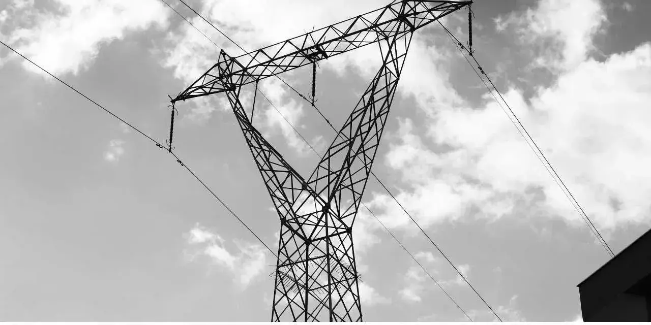 Wysoki słup energetyczny z przewodami, na tle nieba z chmurami. Te linie przesyłowe są kluczowe dla dostarczania energii.