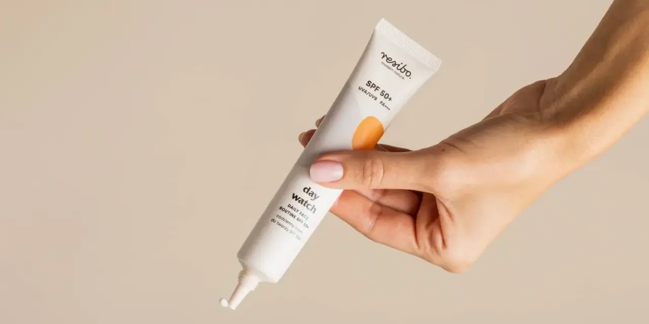 Dłoń trzyma tubkę kremu z filtrem SPF 50+, idealnego do codziennej pielęgnacji. To kwintesencja skinimalizmu – prostota i skuteczność.