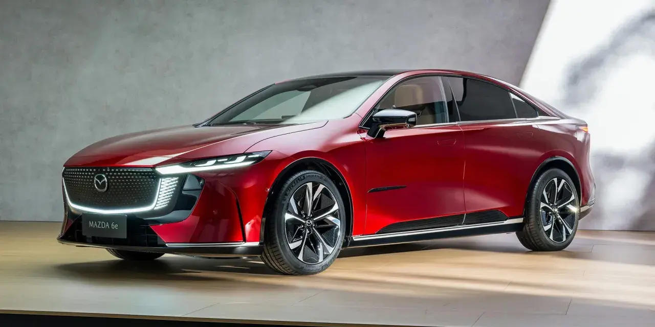 Elegancka, czerwona mazda elektryczna z nowoczesnym designem, prezentowana na drewnianej scenie.