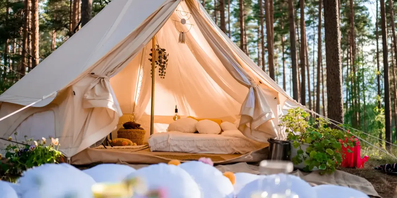 Przytulny namiot w lesie, idealny na glamping w Polsce. Wygodne łóżko, dekoracje i otoczenie natury tworzą magiczną atmosferę.