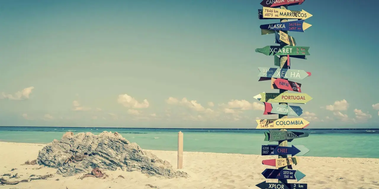 Strand mit Schildern zu fernen Zielen. Ein Traum für ein **auslandsjahr kostenlos**?