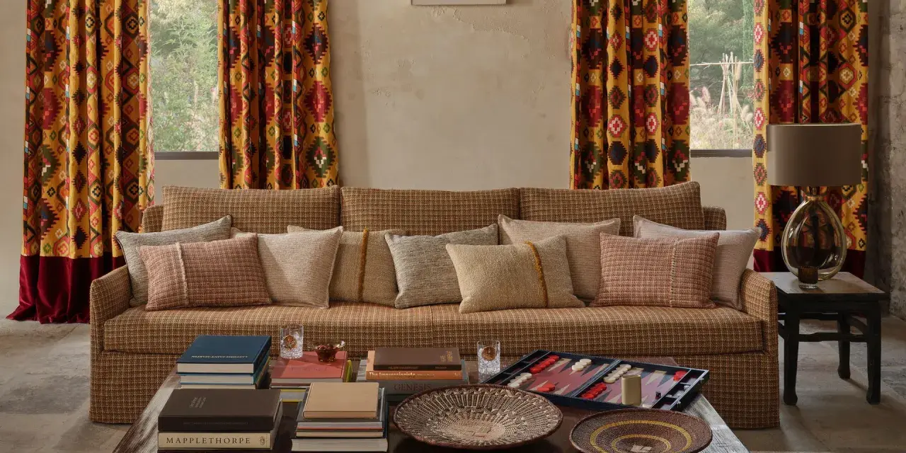 Cortinas con estampado geométrico vibrante, un sofá acogedor y cojines texturizados. Las ultimas tendencias cortinas salon se reflejan en este espacio.