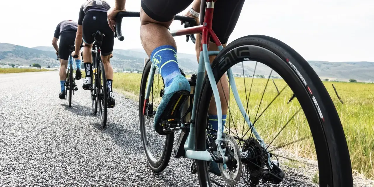 Cyclists on an endurance bike vs road bike race down a gravel road, showcasing their gear and determination.