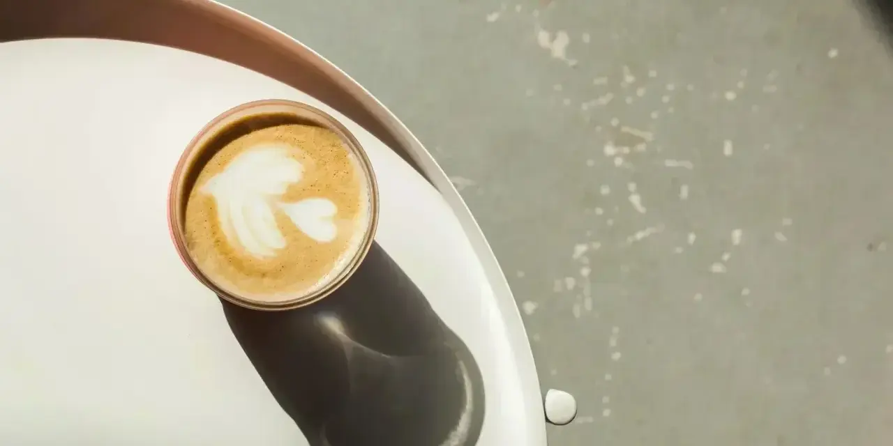 Idealna kawa flat white z pianką w kształcie liścia, podana na tacy.