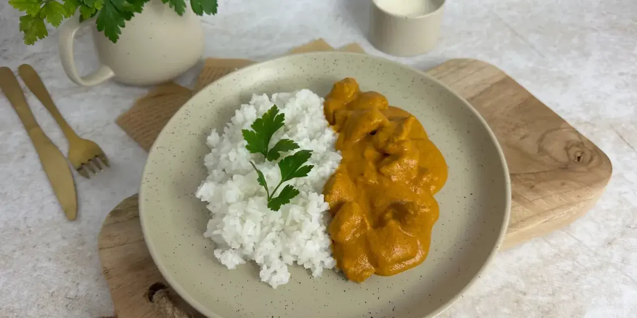 Pyszny Butter Chicken przepis na talerzu z ryżem i natką pietruszki. Idealny obiad.