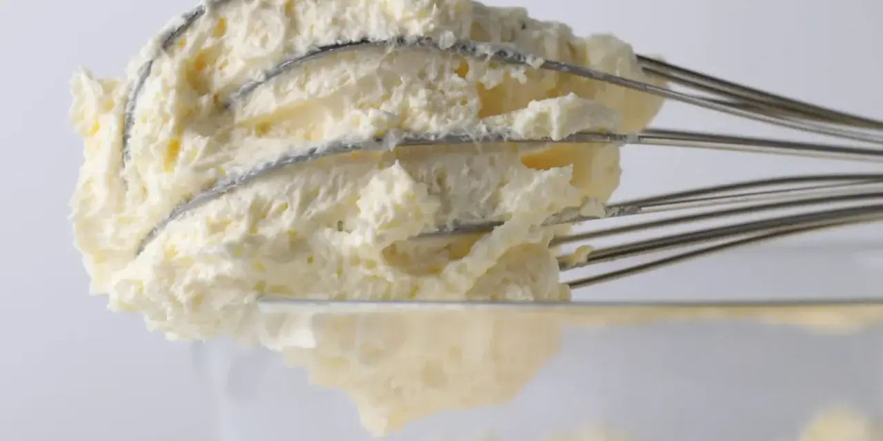 Puszysty krem z mascarpone, ubijany na drucianych trzepaczkach miksera, gotowy do deseru.