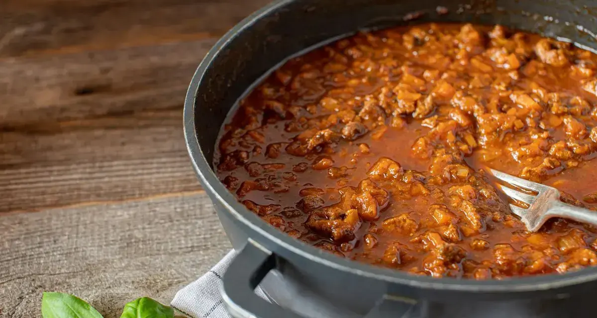Un saporito ragù di anatra, ricetta veneta, pronto in padella con una forchetta. Profumo di basilico fresco.