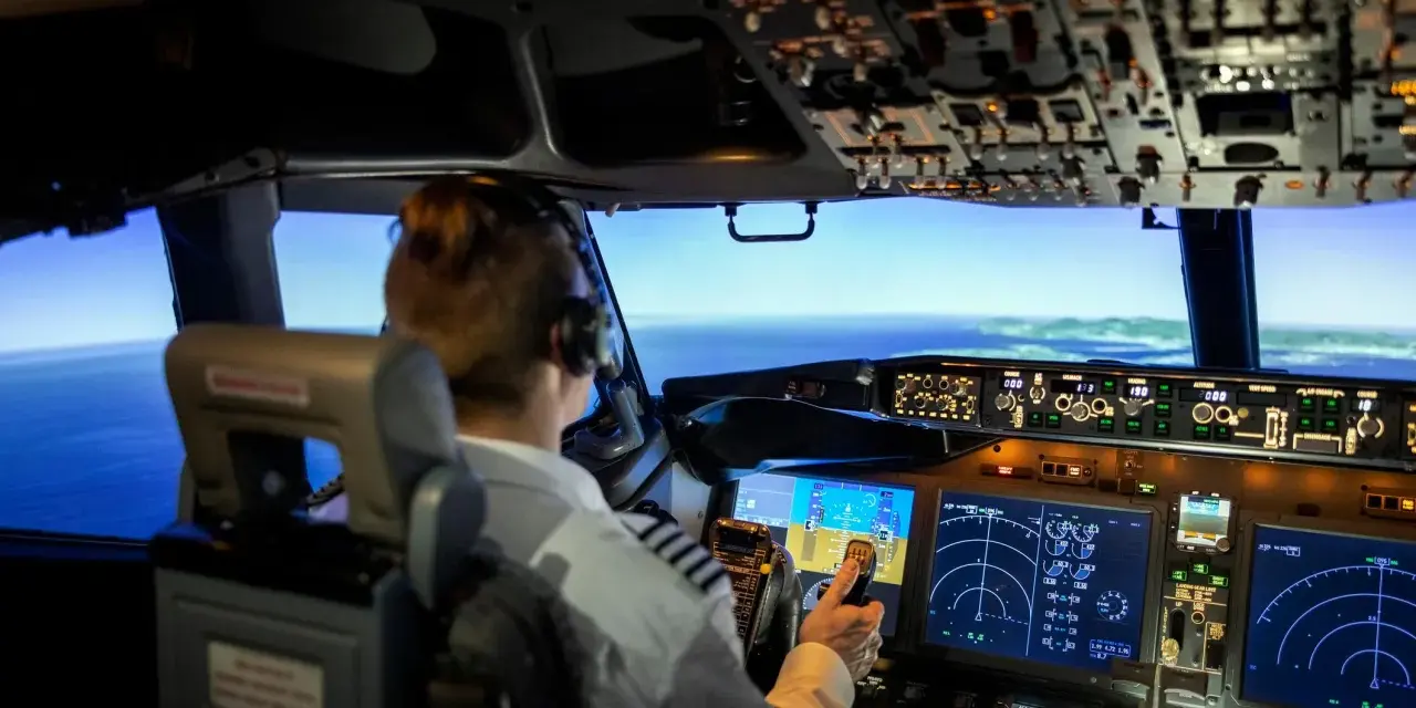 Pilota in cabina di pilotaggio, con schermi e comandi. Chissà quanto guadagna un pilota di aerei per gestire un volo così complesso.