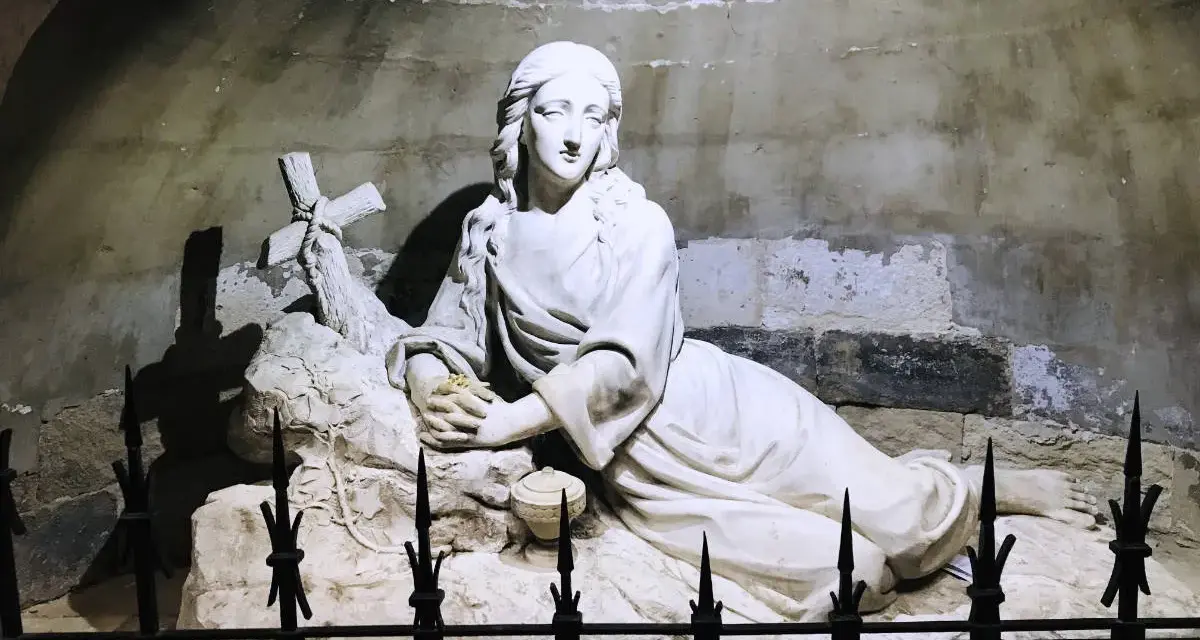 Sculpture of Mary Magdalene in repose, near a cross, possibly at her burial site.
