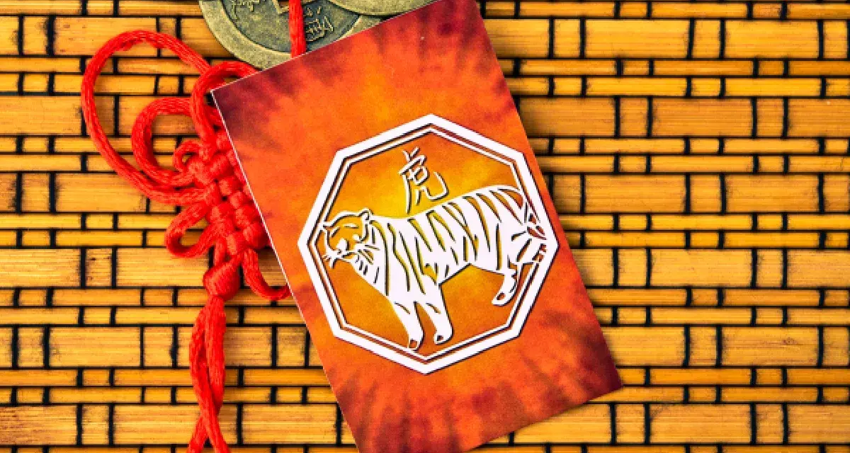 Czerwona ozdoba z tygrysem, symbolem chińskiego znaku zodiaku, na tle bambusowym.