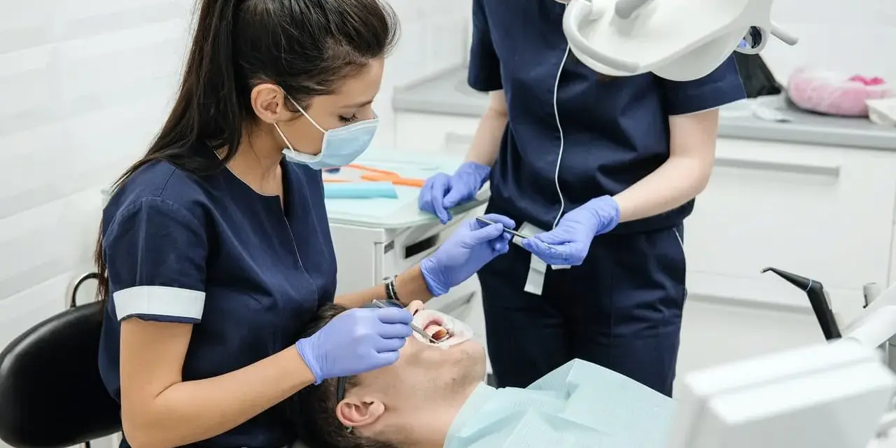 Dentystka wykonuje zabieg. Dowiedz się, jaka jest usuwanie zębów pod narkozą cena i jak przebiega.