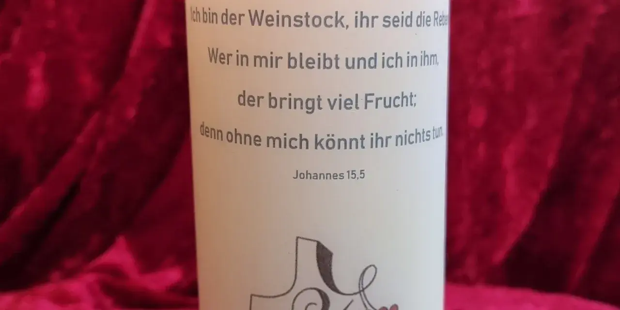 Der Text auf der Kerze zitiert Johannes 15,5: "Ich bin der Weinstock, ihr seid die Rebe. Wer in mir bleibt und ich in ihm, der bringt viel Frucht; denn ohne mich könnt ihr nichts tun.