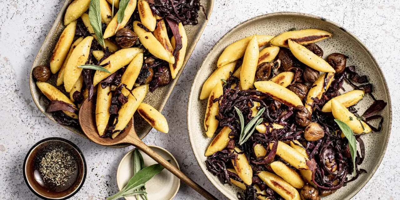 Schupfnudeln mit Rotkohl und Kastanien, garniert mit Salbei. Ein herzhaftes Gericht, das zum Genießen einlädt.