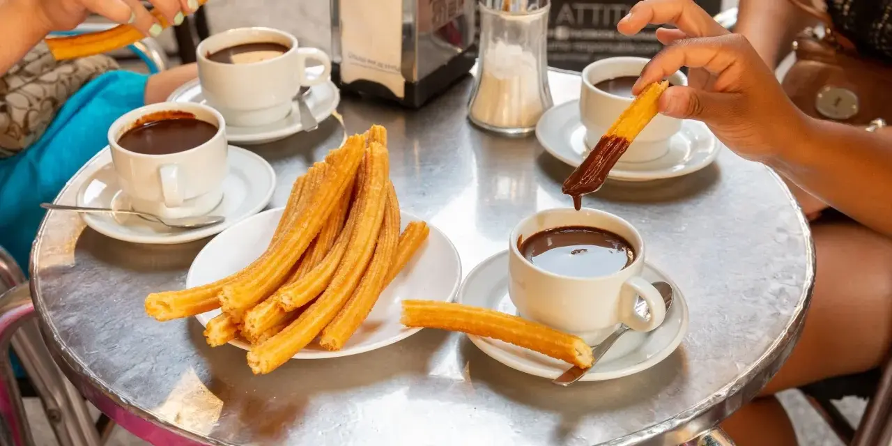 Assaporare i churros con cioccolata calda è un must per sapere cosa mangiare a Madrid. Un'esperienza golosa da condividere.