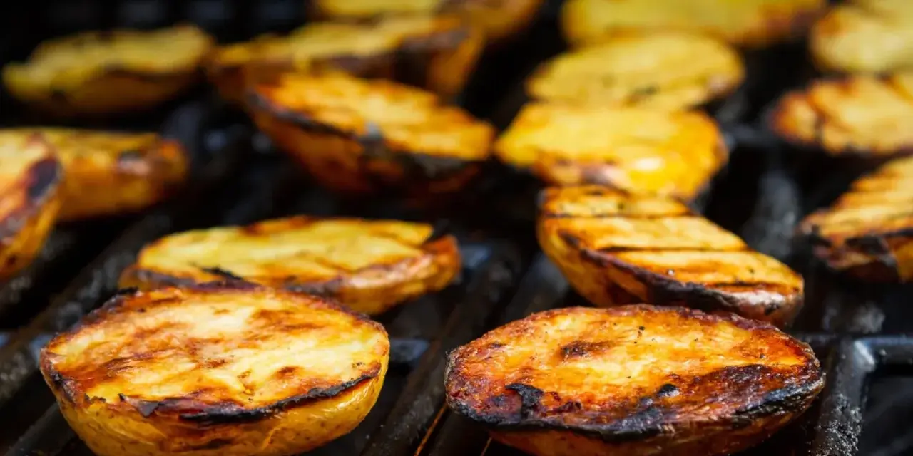 Patate alla griglia dorate e succulente, con segni di cottura perfetti, pronte per essere gustate.
