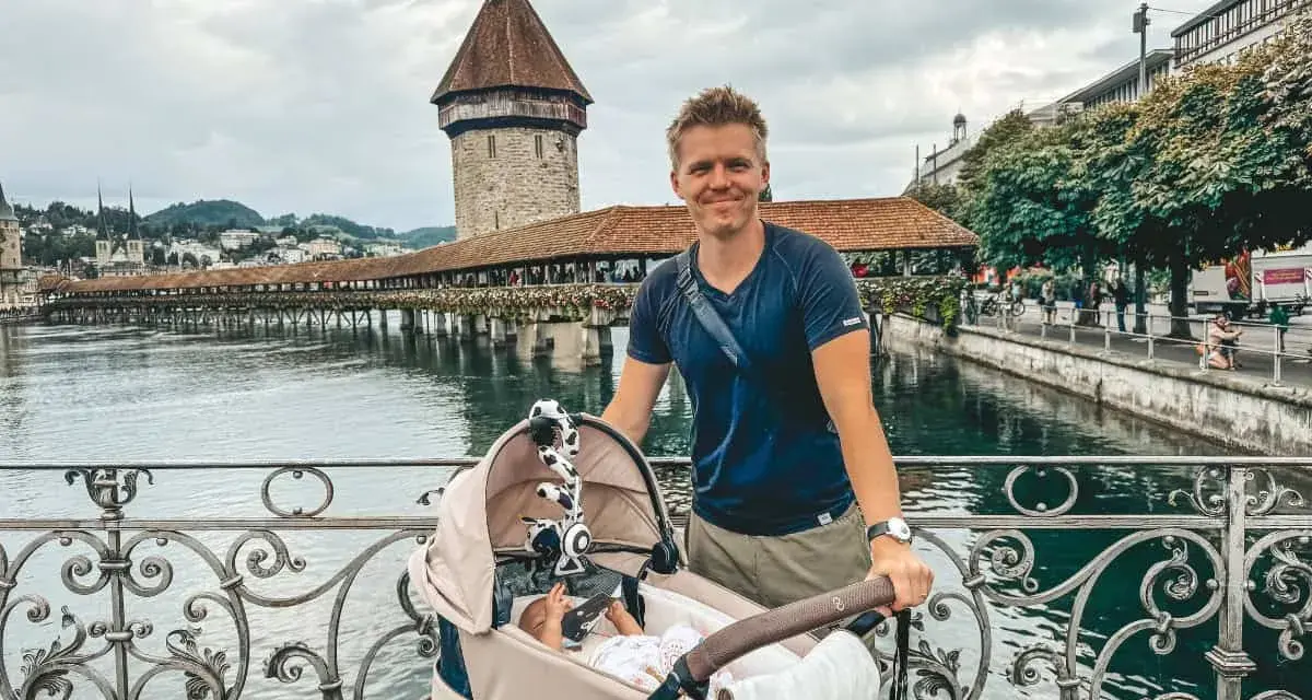 Szczęśliwy ojciec z niemowlakiem w wózku na moście, idealne miejsce, gdzie na wakacje z niemowlakiem.
