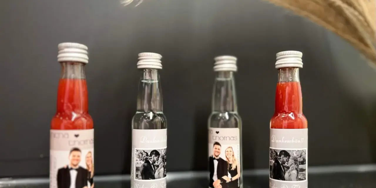 Vier kleine Flaschen mit personalisierten Etiketten, die Hochzeitsfotos und Namen zeigen. Perfekt als Schnaps zum selber machen für Gäste.