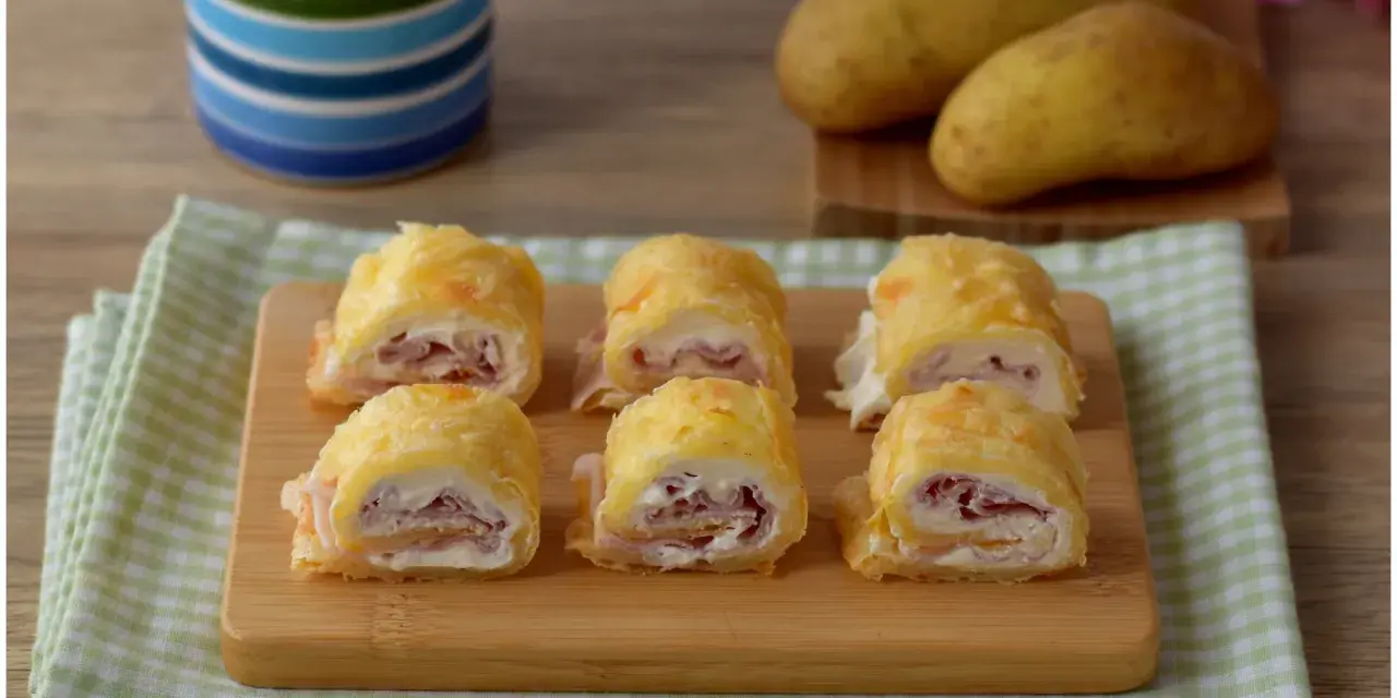 Sei rotoli di patate ripieni di prosciutto e formaggio cremoso, pronti per essere gustati.
