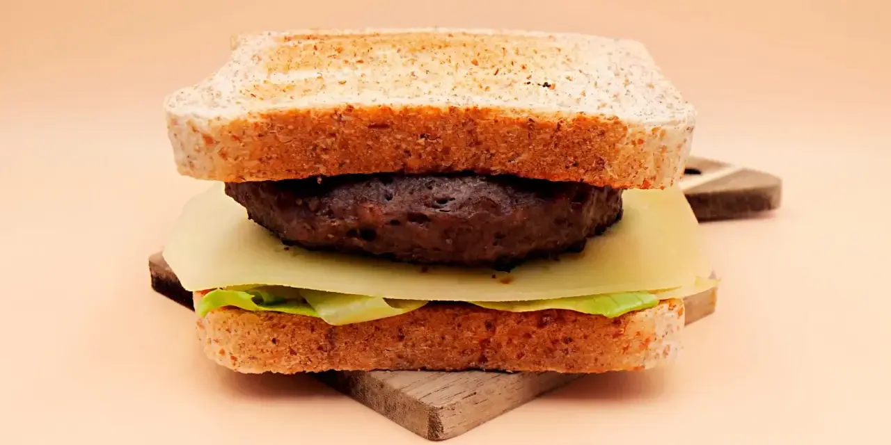 Burger z wołowiny, serem, sałatą i tostami na desce.