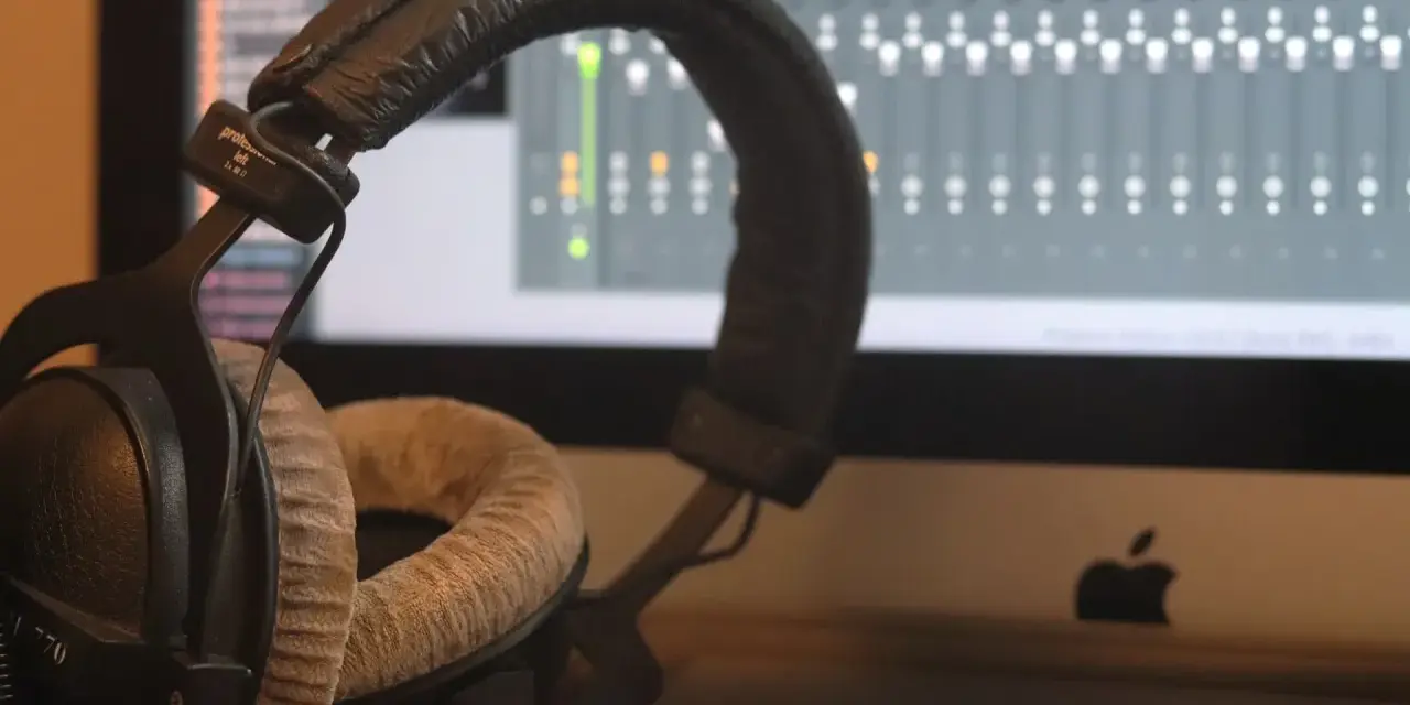 Słuchawki studyjne na tle ekranu z mikserem. Idealne do tworzenia muzyki w domowym studio nagrań.