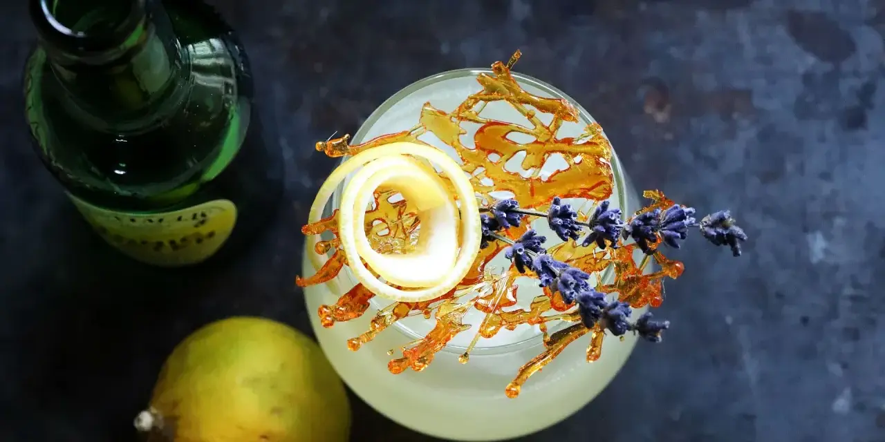 Erfrischender Drink mit Zitronenzeste, Karamell und Lavendel. Die bergamotte verwendung in Cocktails ist ein Genuss.