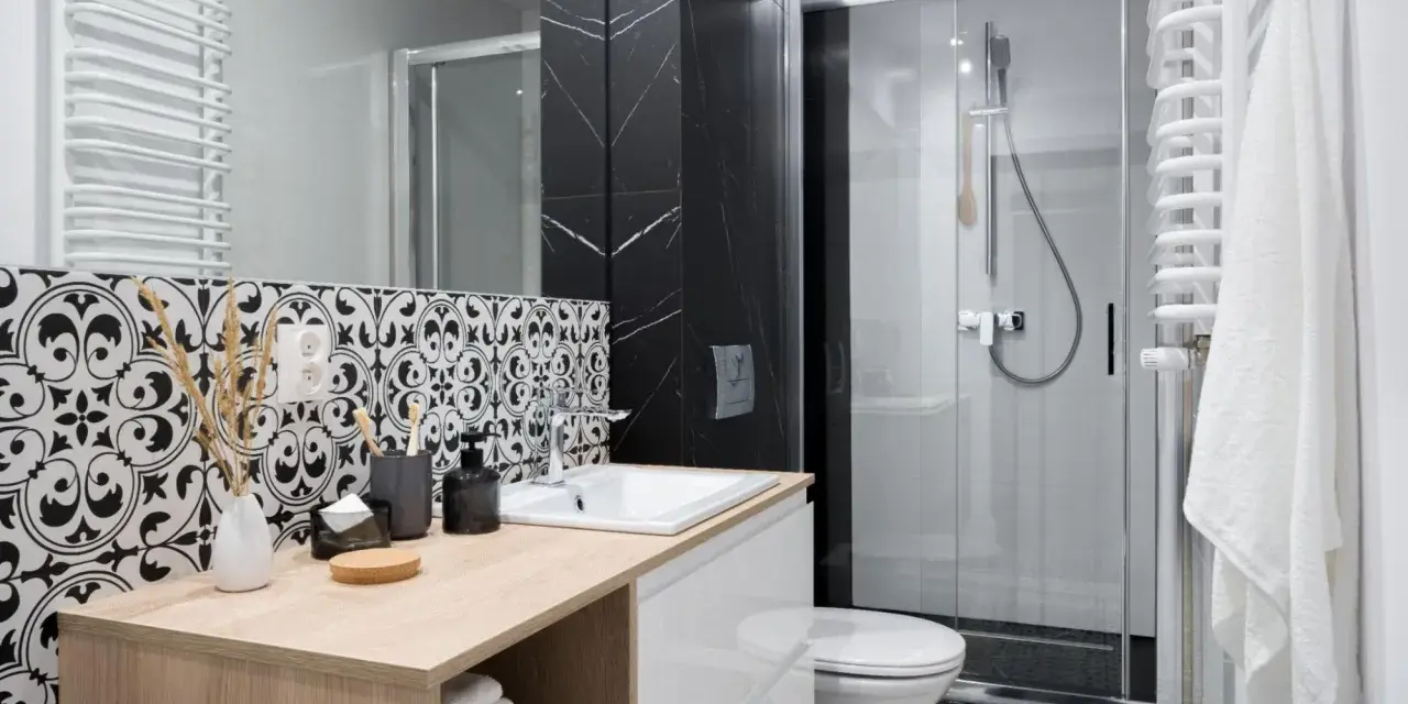 Élégante petite salle de bain italienne avec carrelage noir et blanc, douche moderne et meuble vasque en bois clair.