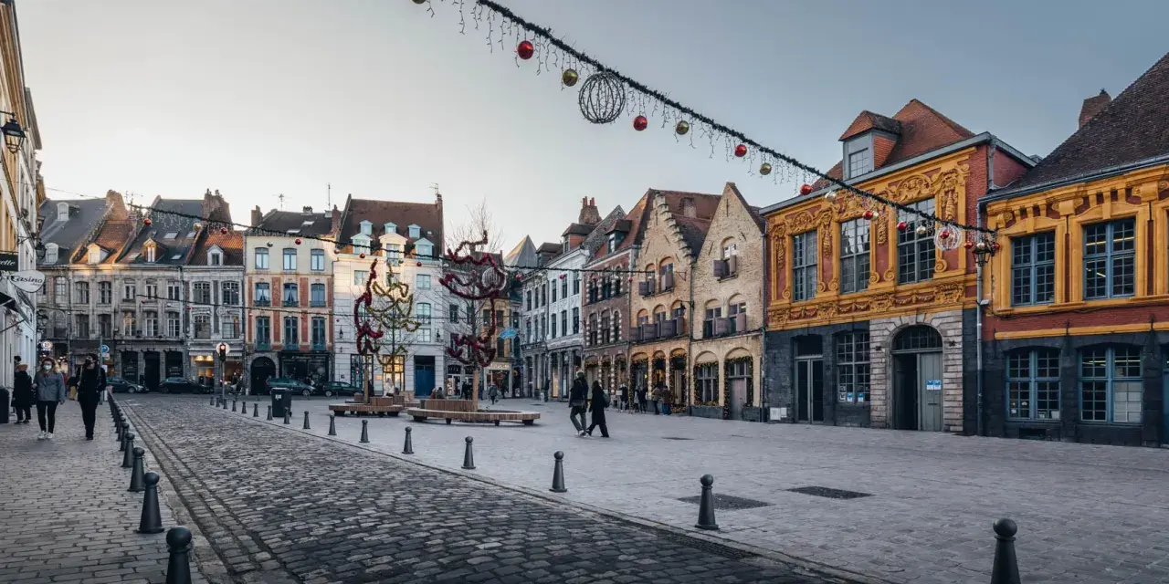 La Place du Théâtre à Lille, ornée de décorations de Noël, révèle les plus belles rues du Vieux-Lille avec ses façades colorées et pavées.