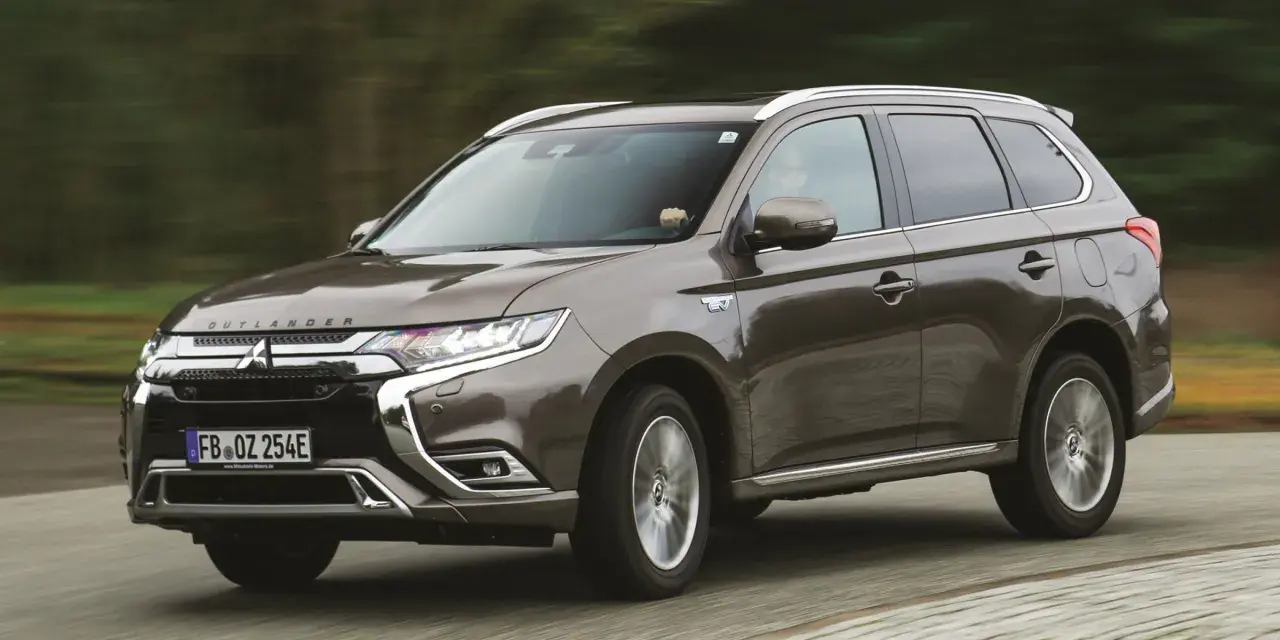 Brązowy Mitsubishi Outlander PHEV jedzie po drodze, zamazane tło sugeruje ruch.