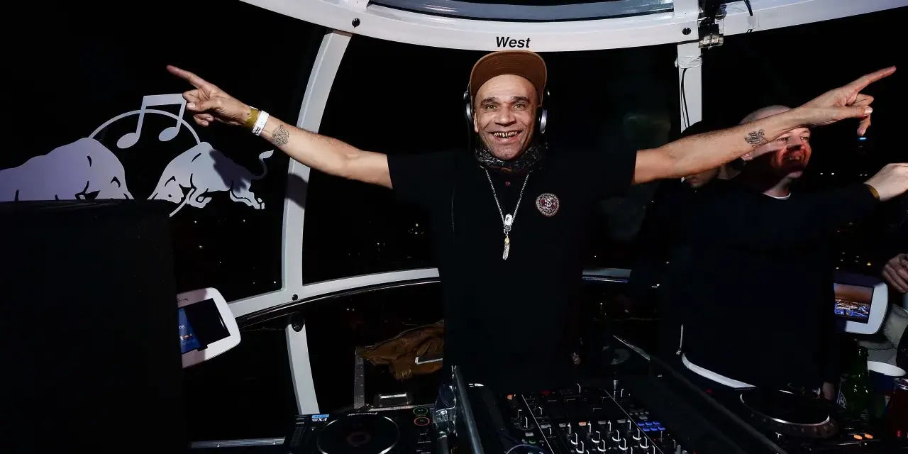 Un dj rap souriant, casqué, bras écartés, anime la soirée dans une cabine panoramique.