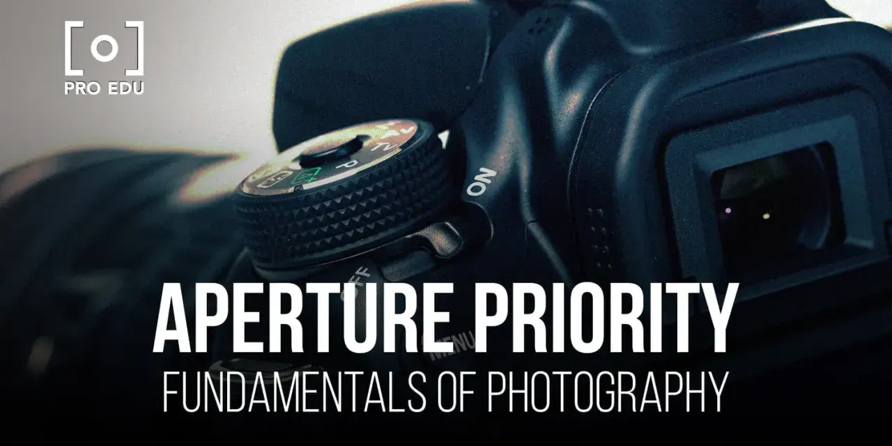 Gros plan sur un appareil photo, avec le texte "APERTURE PRIORITY" et "FUNDAMENTALS OF PHOTOGRAPHY". Le mode priorité ouverture est essentiel pour maîtriser la profondeur de champ.