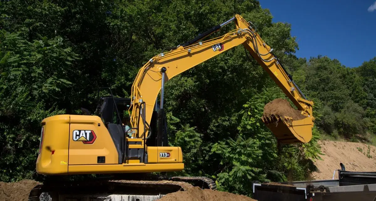 Żółta koparka Cat 313 z łyżką pełną ziemi, gotowa do pracy. Dane techniczne tej maszyny budowlanej są imponujące.