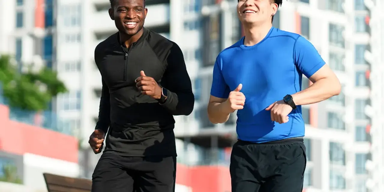 Deux hommes souriants courent ensemble dans un parc, profitant de leur routine pour courir tous les jours.