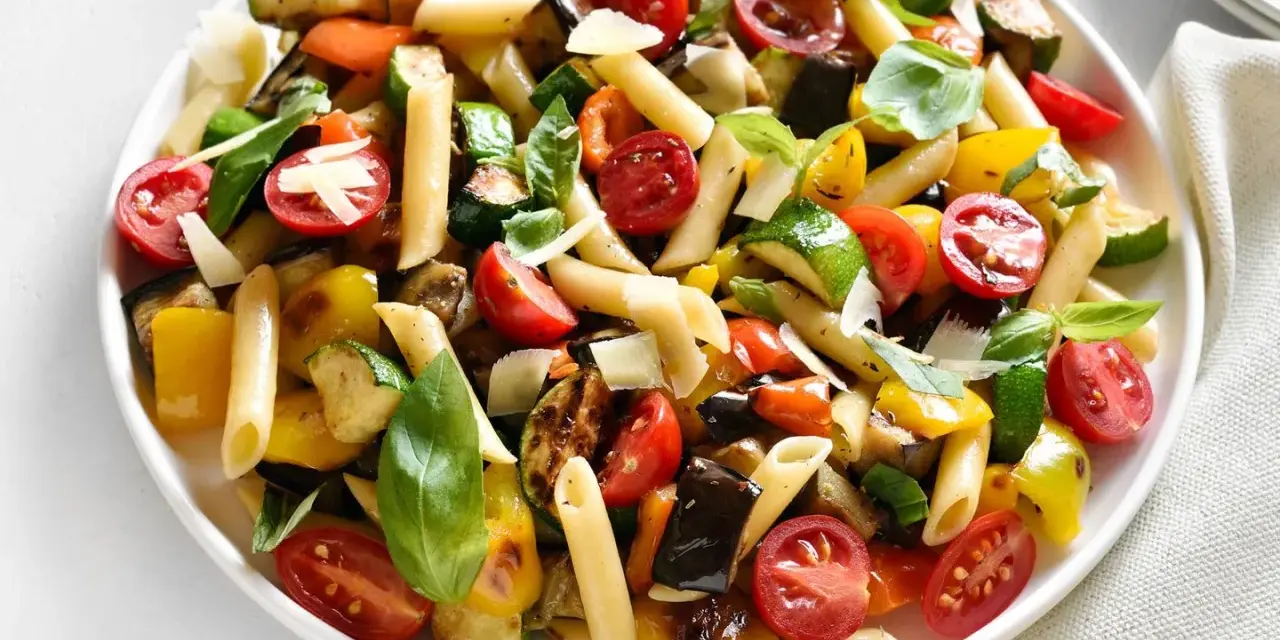 Bunter Nudelsalat ohne Mayo mit Penne, gegrilltem Gemüse wie Zucchini, Aubergine, Paprika, Kirschtomaten und frischem Basilikum, garniert mit Parmesan.