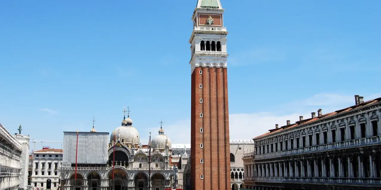 La maestosa altezza del campanile di San Marco domina Piazza San Marco, con la Basilica sullo sfondo e la folla che passeggia.