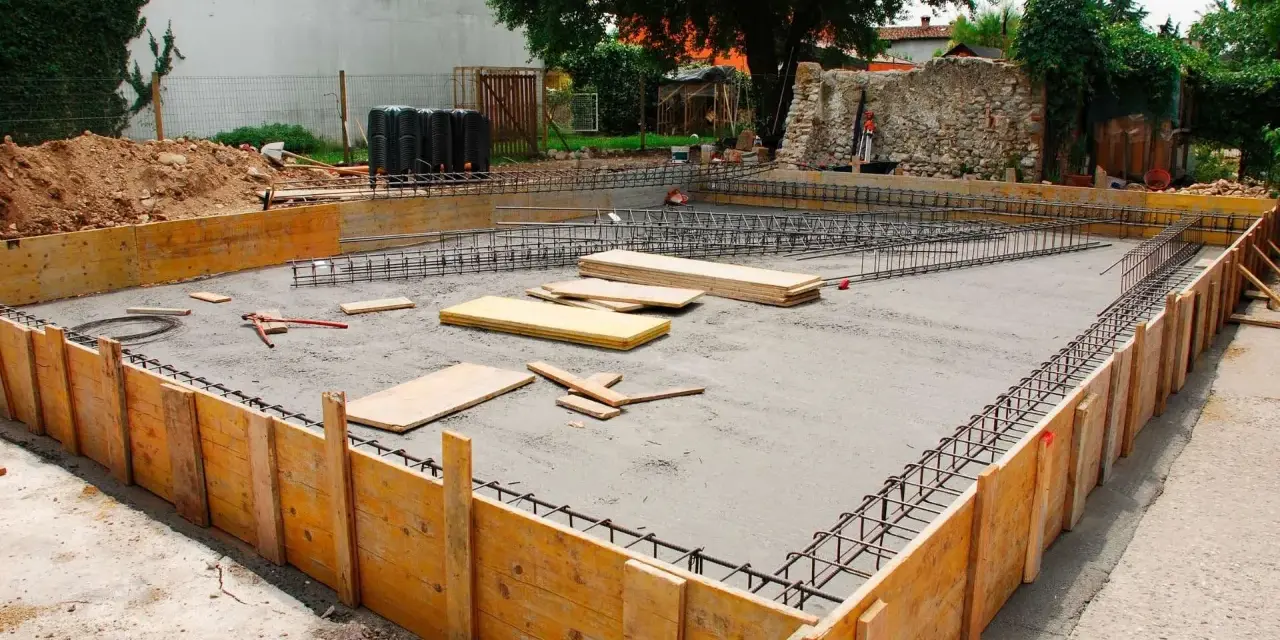 Drewniane szalunki i zbrojenie czekają na beton, tworząc fundamenty z kamienia.