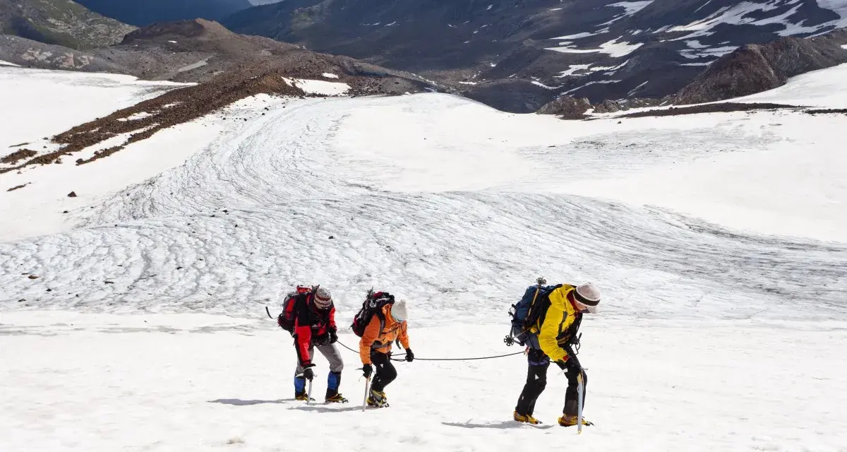 Drei Bergsteiger seilen sich über einen eisigen Gletscher in den Alpen ab.