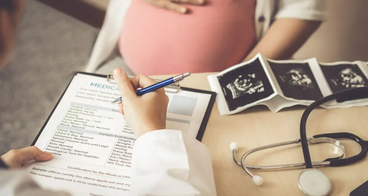 Medico compila cartella clinica con ecografie e stetoscopio. L'autismo si può diagnosticare in gravidanza, con controlli precoci.